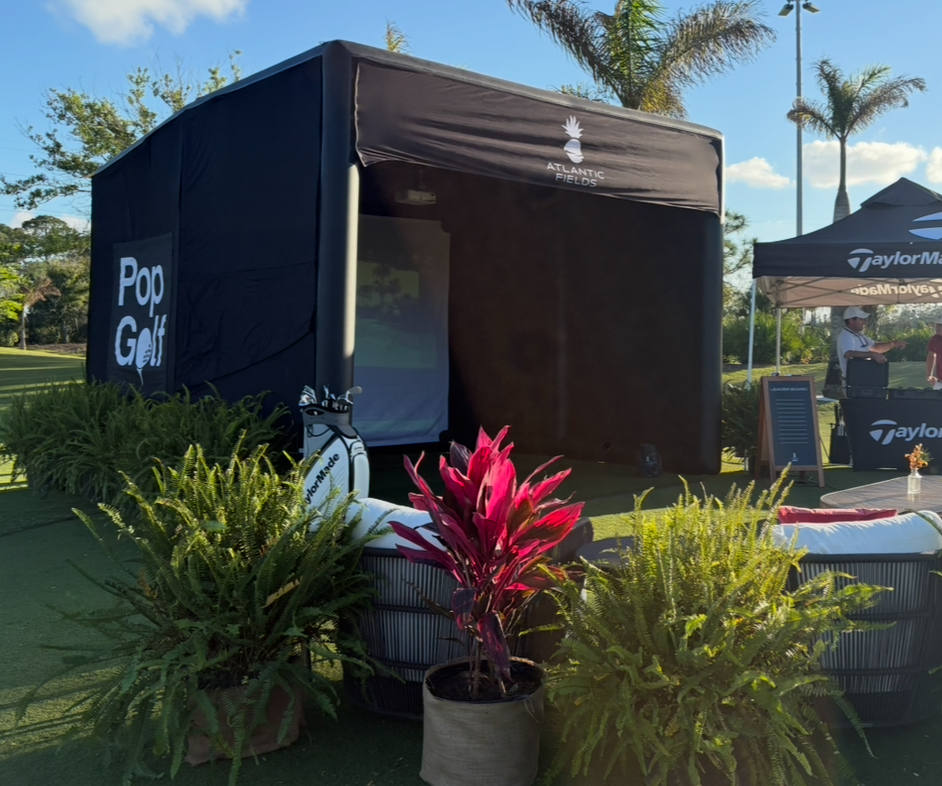 PopGolf simulator branded for Atlantic Fields set up on a resort lawn with lounge seating and tropical landscaping