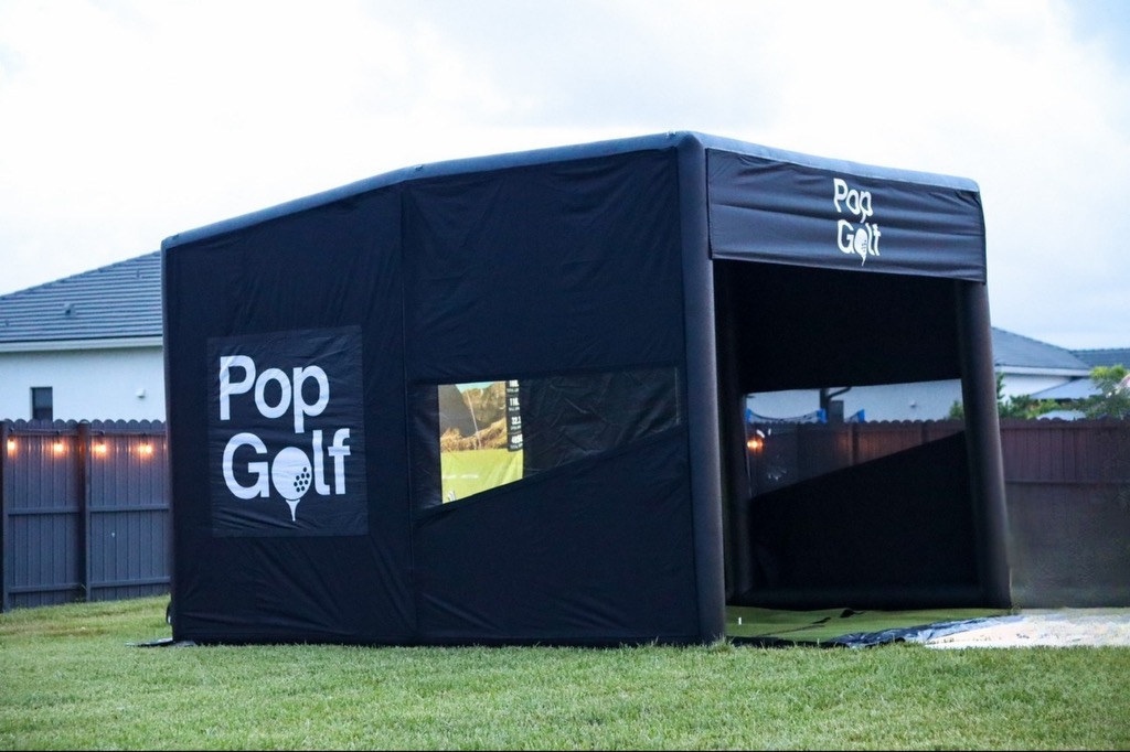 PopGolf simulator branded with logos set up in a private backyard at dusk